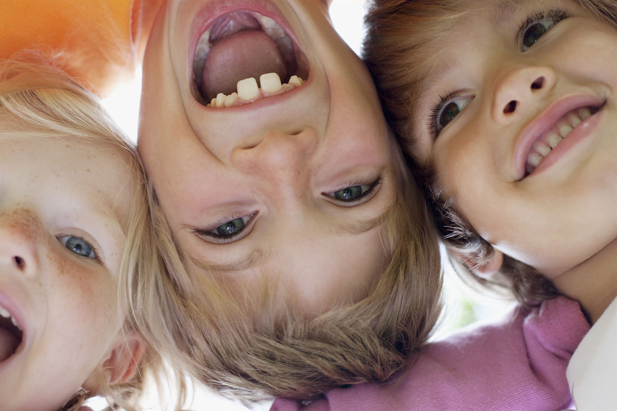 Smiling-faces-of-three-children-with-heads-side-by-side,-head-in-center-appears-upside-down